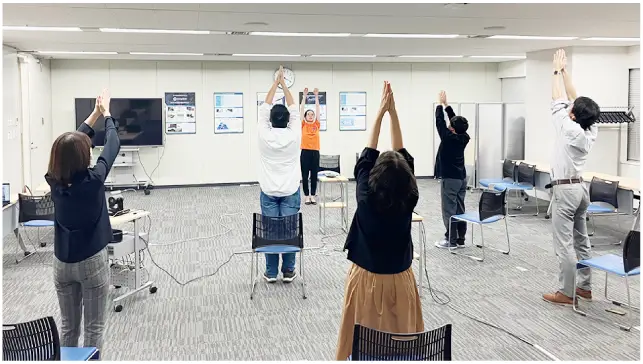 会議室でストレッチ体操をする社員たち