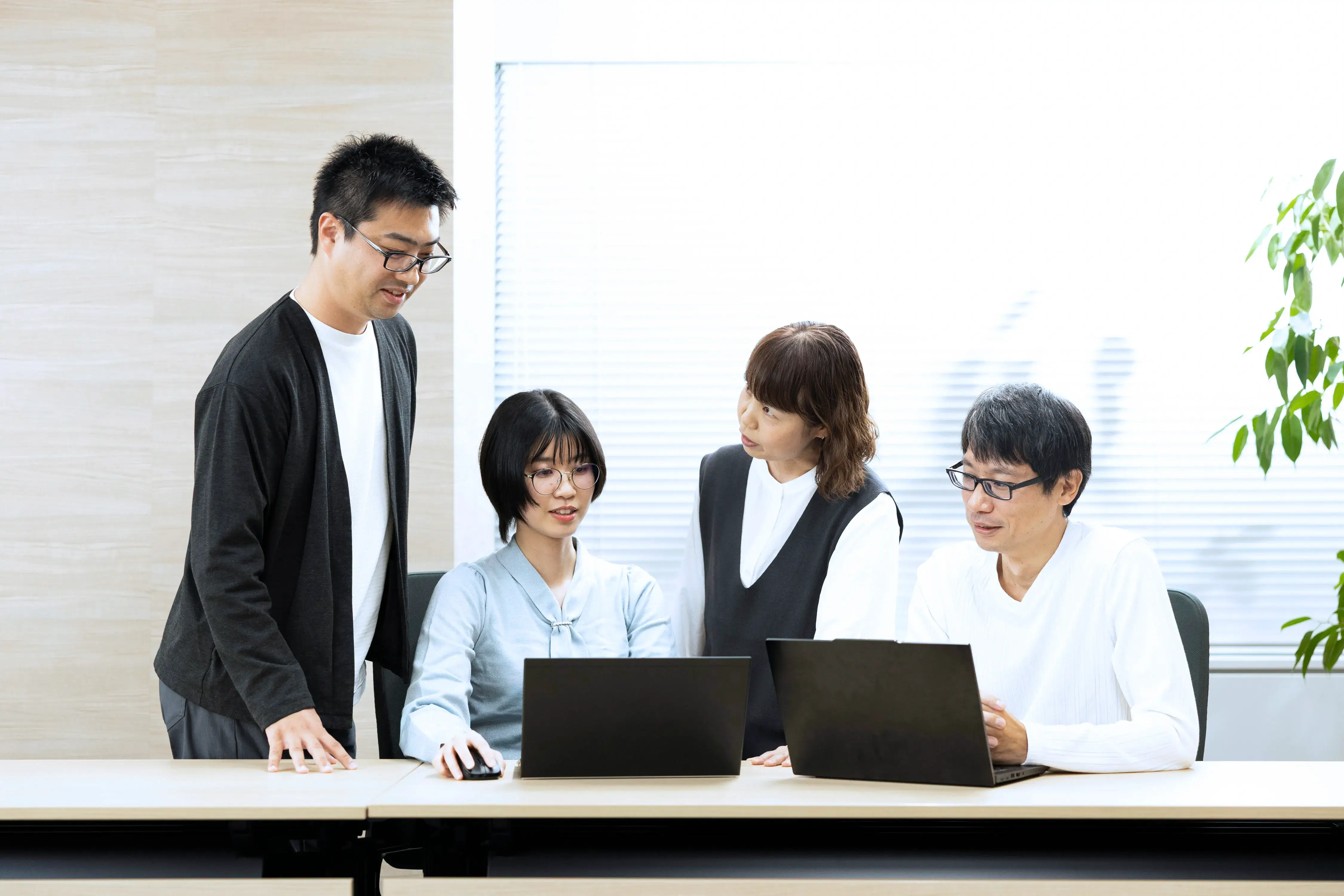 チームでノートPCを囲み業務に取り組む社員たち